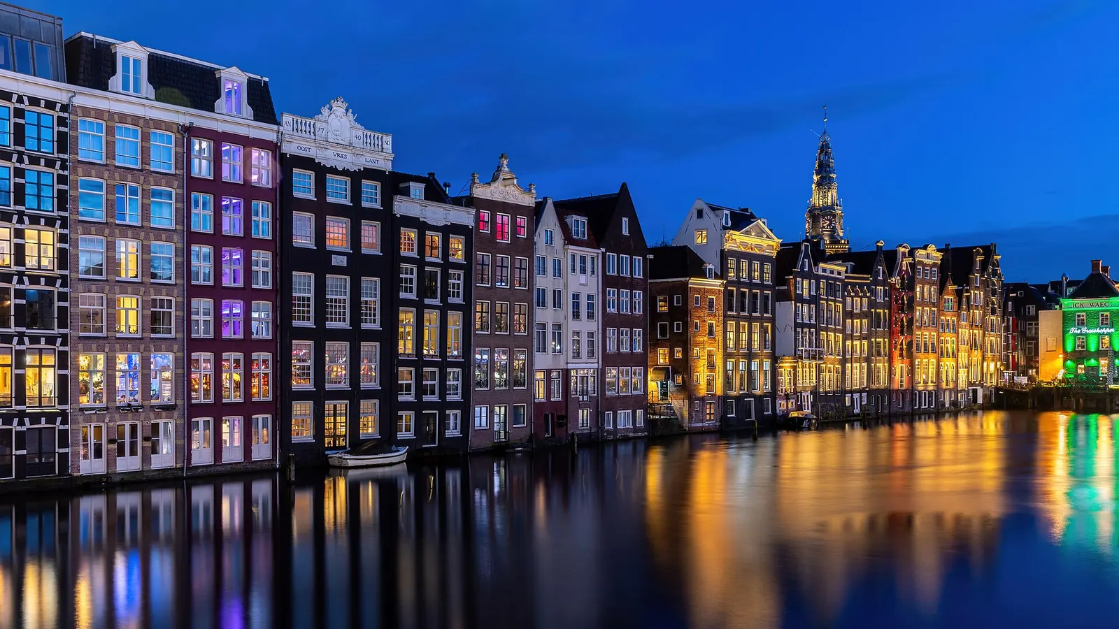 Les maisons colorées du Damrak se reflétant dans l'eau à l'heure bleue