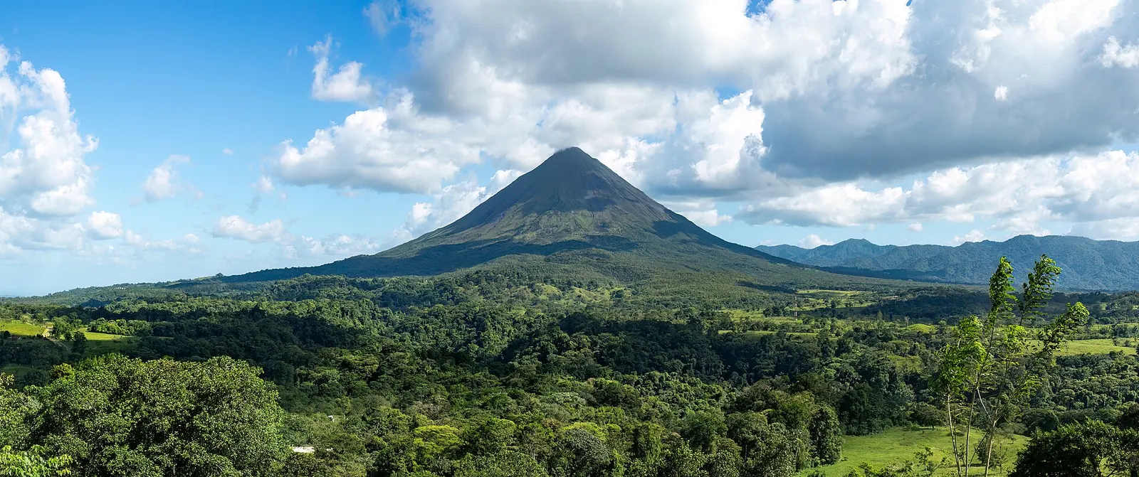 The cone of Arenal Volcano above green Costa Rican countryside